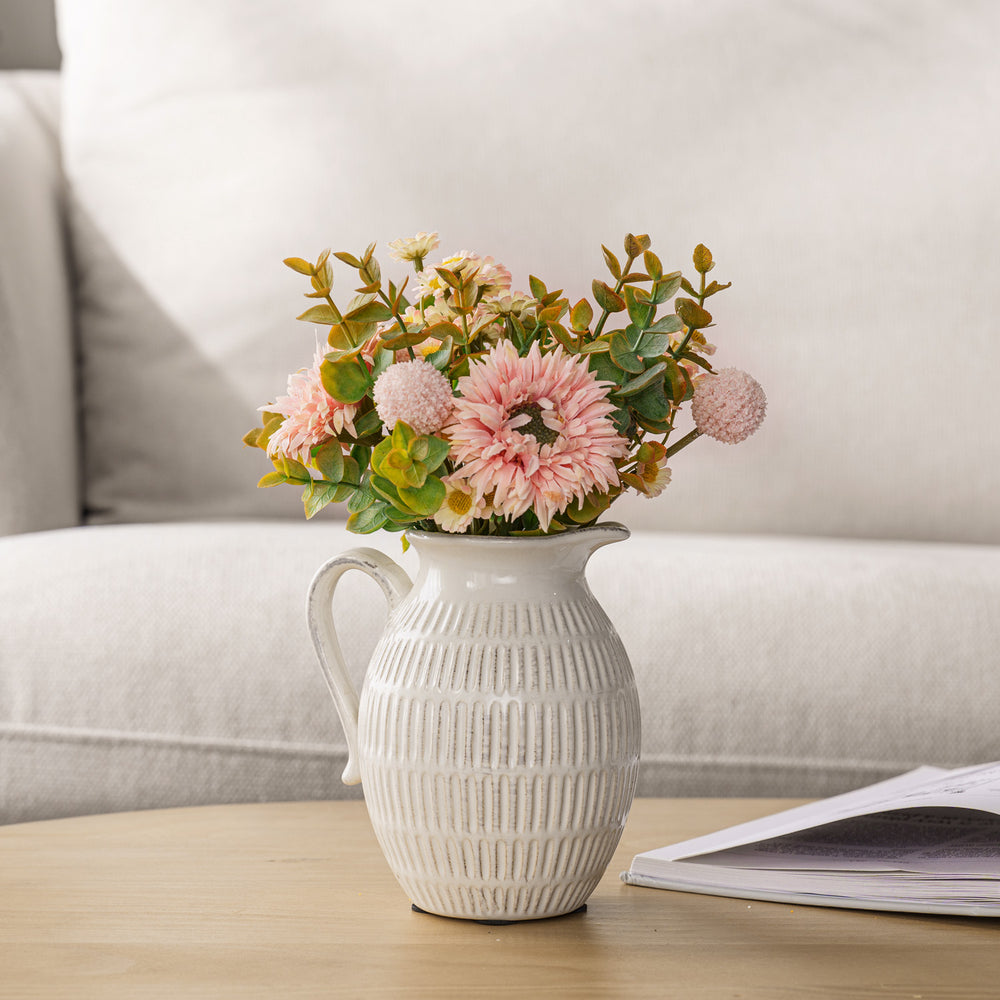 Spring bouquet in off white ceramic pitcher vase on coffee table